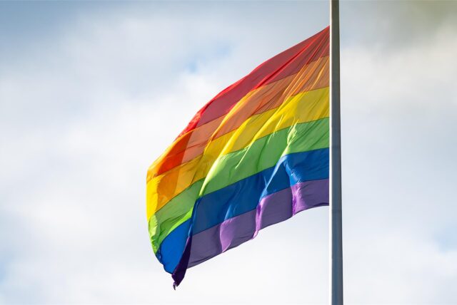 Eine Regenbogenfahne flattert im Wind.