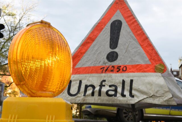 Ein Warnlicht steht vor einem Polizeiwarndreieck mit der Aufschrift „Unfall“.