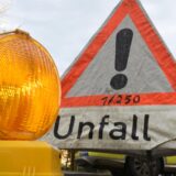 Ein Warnlicht steht vor einem Polizeiwarndreieck mit der Aufschrift „Unfall“.