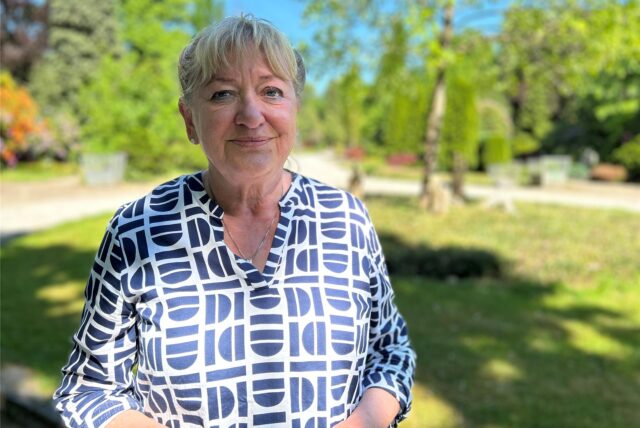 Marita Eckart steht auf dem Hauptfriedhof in Datteln, hinter ihr viel Grün.