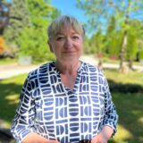 Marita Eckart steht auf dem Hauptfriedhof in Datteln, hinter ihr viel Grün.