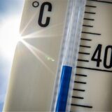 Ein Außenthermometer zeigt vor dem blauen Himmel und der Sonne eine Temperatur von nahezu 40 Grad Celsius an. (Archivbild)