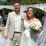 Kevin und Vivien Charizanis stehen an ihrem Hochzeitstag am klein glücklich in Horneburg vor einem Tuch mit herzförmigem Loch.