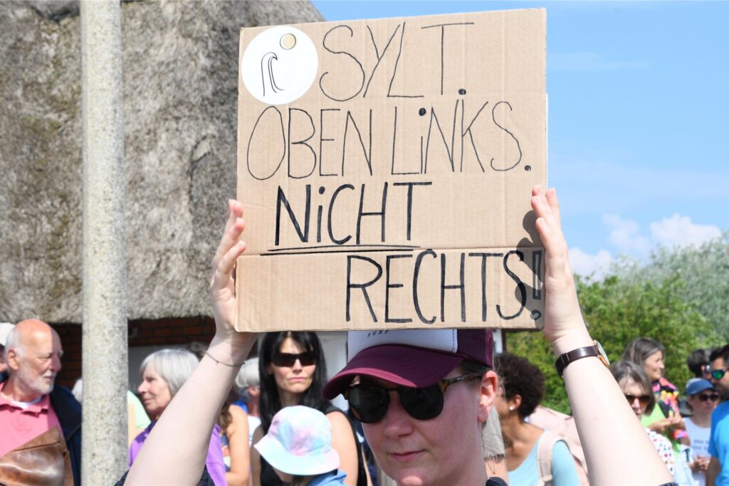„Sylt oben links nicht rechts“ steht auf einem Plakat, dass eine Frau bei einer Mahnwache am 26.05.2024 auf Sylt in der Hand hält. „Sylt oben links nicht rechts“ steht auf einem Plakat, dass eine Frau bei einer Mahnwache am 26.05.2024 auf Sylt in der Hand hält.