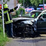 Ein Auto ist gegen ein Schild gefahren, Feuerwehrleute stehen am Wagen.