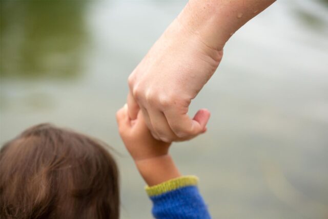 Kind hält Hand von erwachsener Person