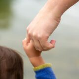 Kind hält Hand von erwachsener Person