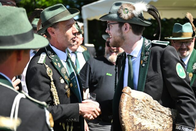 Vier Schützen tragen einen weiteren Schützen auf den Schultern. Der hält Reste eines Holzvogels in den Händen.