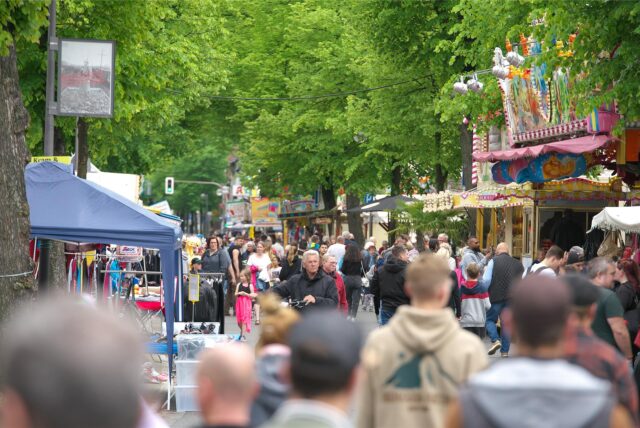 Menschen auf einem Straßenfest mit Kirmesbuden.