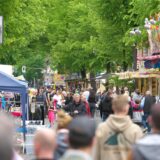 Menschen auf einem Straßenfest mit Kirmesbuden.
