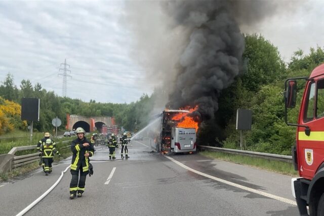 Feuerwehrkräfte löschen auf der B236 in Dortmund einen brennenden Reisebus.