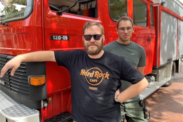 Tim Stracke und Eric Wessendorf stehen neben einem Feuerwehr-Oldtimer.