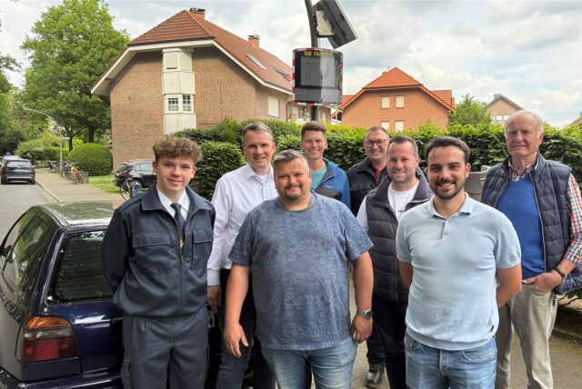 Menschen stehen vor einer Geschwindigkeitsmesstafel.