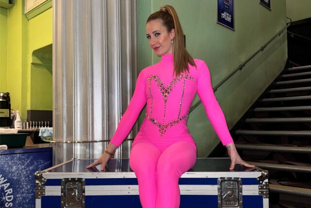 Charlotte Osigus vom TanzExpress Haltern sitzt im pinken, glitzernden Bühnenoutfit auf einer Truhe mit dem Schriftzug „Britain’s got Talent“.