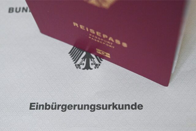 Ein Reisepass steht auf einer Einbürgerungsurkunde