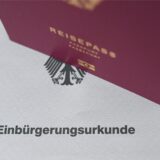 Ein Reisepass steht auf einer Einbürgerungsurkunde