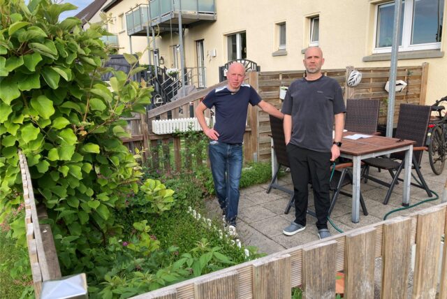 Zwei Männer auf einer kleinen Terrasse einer Mietwohnung.