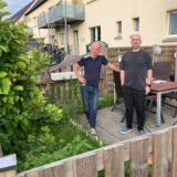 Zwei Männer auf einer kleinen Terrasse einer Mietwohnung.