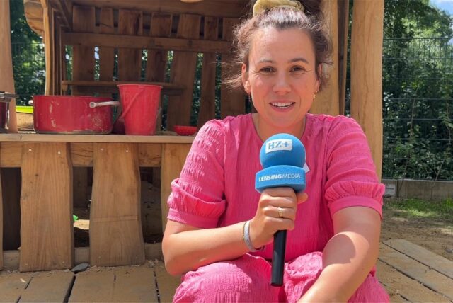 Kita-Leiterin Marie Büning sitzt vor einem der Spielhäuser auf dem Außengelände der Kita Senfkorn in Haltern.
