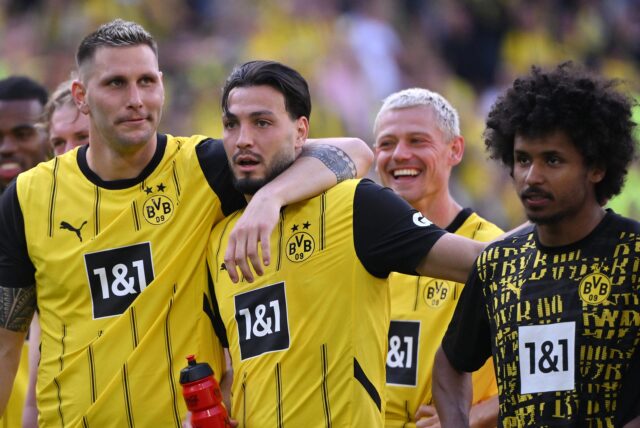 Karim Adeyemi, Ramy Bensebaini und Niklas Süle stehen vor der Südtribüne.