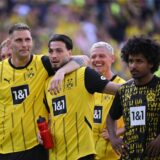 Karim Adeyemi, Ramy Bensebaini und Niklas Süle stehen vor der Südtribüne.