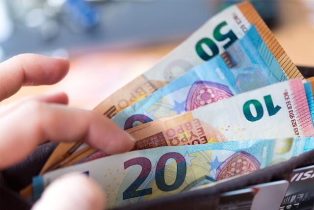 Eine Hand sortiert Geldscheine in einem Portemonnaie.