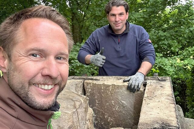 Zwei Männer nehmen die Bruchsteinplatten eines Denkmals auseinander.