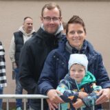 Eine Familie steht an einem Absperrgitter und lächelt in die Kamera.