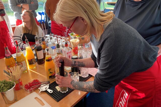 Eine Frau drückt mit einem Stößel eine Limette in einem Glas aus.