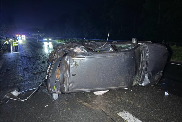 Ein Auto liegt nach einem Unfall beschädigt auf der Seite.