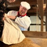 Müller Christian Wiethoff schüttet einen Sack Korn aus.