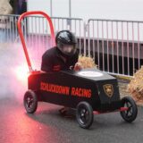 Eine Seifenkiste in Form eines Feuerlöschers wird auf die Startrampe gebracht.