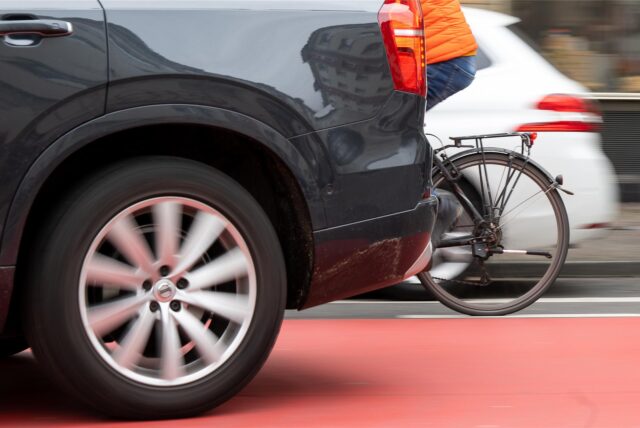 Zwischen zwei Autos kann man das Hinterrad eines Fahrrads sehen.