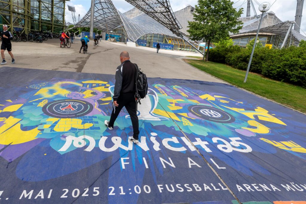 Ein Besucher des Olympiaparks in München läuft über einen Teppich mit der Aufschrift Ein Besucher des Olympiaparks in München läuft über einen Teppich mit der Aufschrift