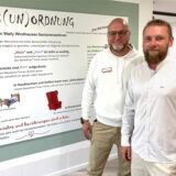 Björn Przybysz (l., Einrichtungsleitung) und Rafael Kus (Pflegedienstleitung) stehen im Wally-Windhausen-Seniorenzentrum in Herten in der dritten Etage, der Gammel-Oase, vor einer großen-Info-Tafel, der Haus(un)ordnung.