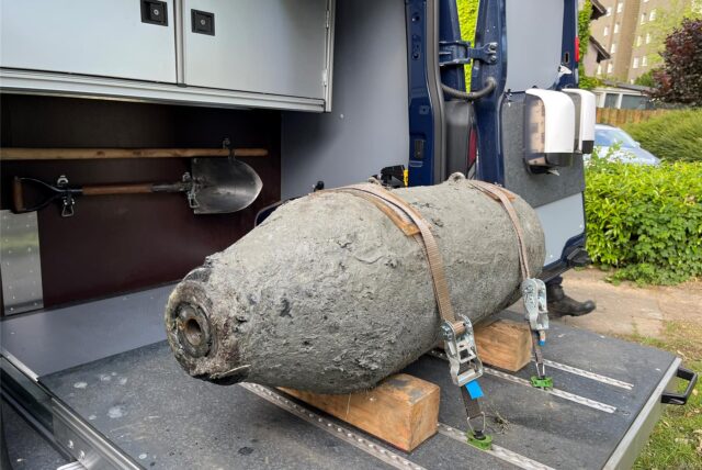 Im Laderaum eines Fahrzeugs liegt eine Weltkriegsbombe. Die Bombe ist mit Gurten gesichert und wird von Holzblöcken stabilisiert.