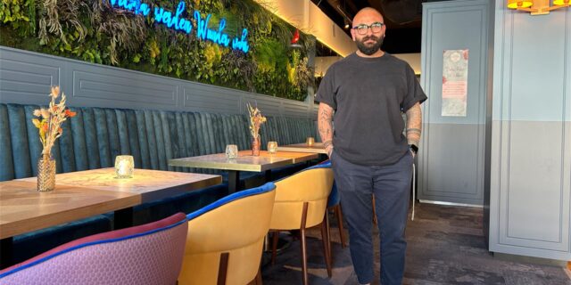 Can Korkmaz, ein Mann mit Bart und Brille, steht in seinem Restaurant.