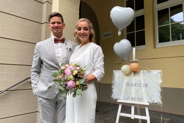 Ein Hochzeitspaar schaut in die Kamera.
