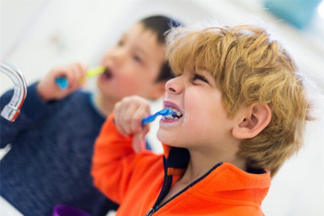 Zwei Kinder putzen sich mit Kinderzahnpasta die Zähne.