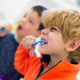 Zwei Kinder putzen sich mit Kinderzahnpasta die Zähne.