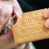 Eine Frau beißt in einen Leibniz-Butterkeks.