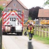 Ein Fahrzeug der Feuerwehr steht auf dem Gelände eines landwirtschaftlichen Betriebes in Gladbeck. Im Vordergrund geht ein Feuerwehrmann in voller Montur über einen gepflasterten Weg.