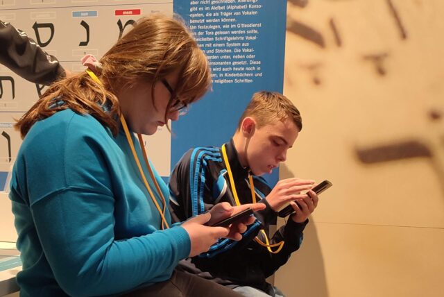 Jugendliche probieren die neue Tonspur auf dem Medienguide im Jüdischen Museum Westfalen aus.