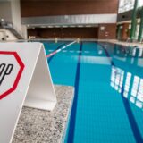Symbolbild: „Stop“ steht auf einem Schild auf einem gesperrten Startblock am Beckenrand eines Hallenbads.