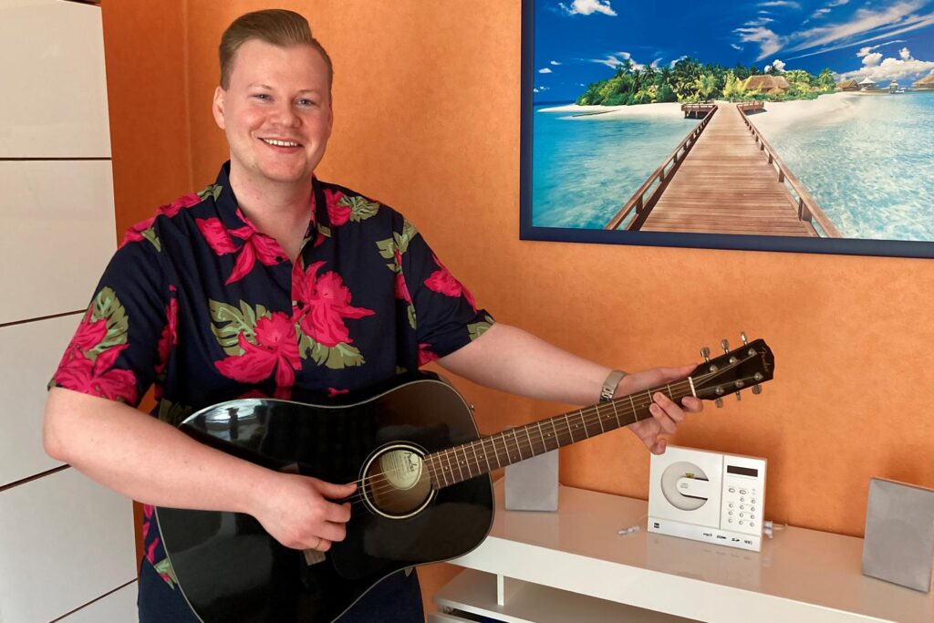 Der Hertener Schlagersänder Steven Loyd steht in einem Wohnzimmer und hält eine Gitarre in den Händen. Der Hertener Schlagersänder Steven Loyd steht in einem Wohnzimmer und hält eine Gitarre in den Händen.