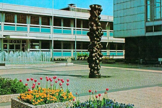 Historische Aufnahme des Otto-Wels-Platzes mit blühenden Blumenkästen im Vordergrund.