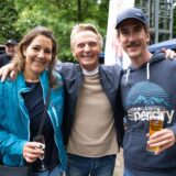 Zwei Männer und eine Frau stehen zusammen und lächeln in die Kamera.