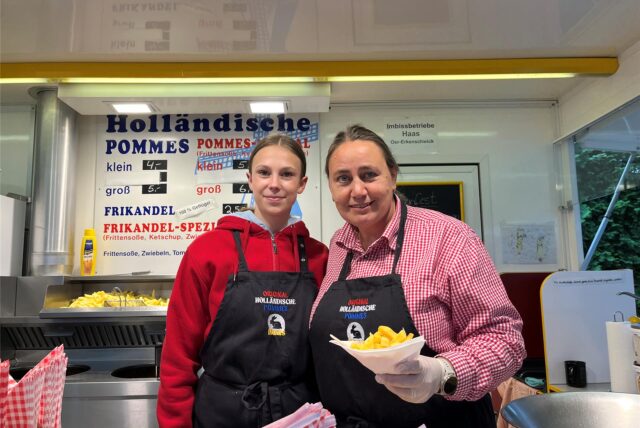 Ein Mächen und eine Frau verkaufen Pommes.