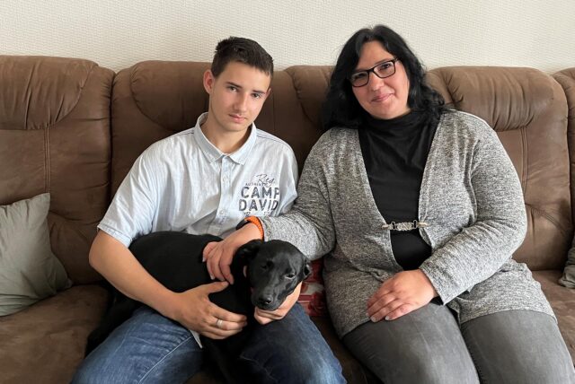 Diana und Dean Tisch mit Hündin Prea auf einer Couch.