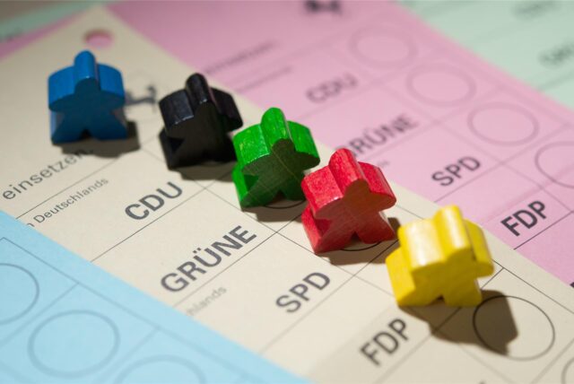 Farbige Spielfiguren stehen am 18.02.2016 in Stuttgart (Baden-Württemberg) auf Wahlscheinen für die Landtagswahl in Baden-Württemberg
